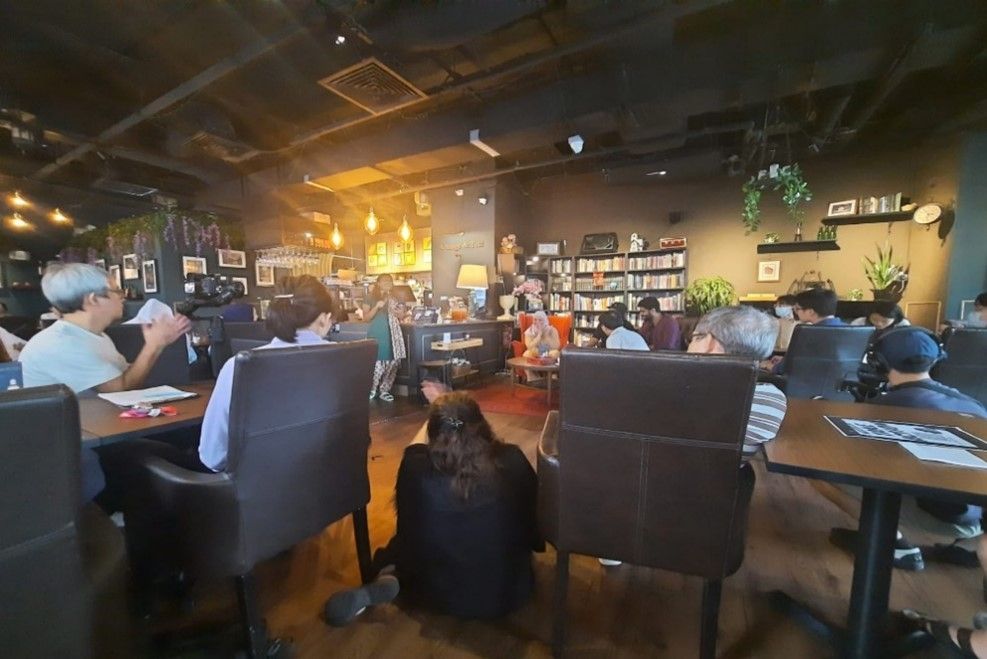 The interior of a cafe with people seated on chairs around tables.