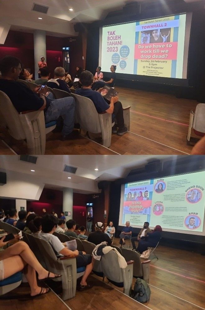 People seated in a cinema theatre, with a semi-circle of chairs and speakers in front of a screen projecting a visual poster for the town halls.